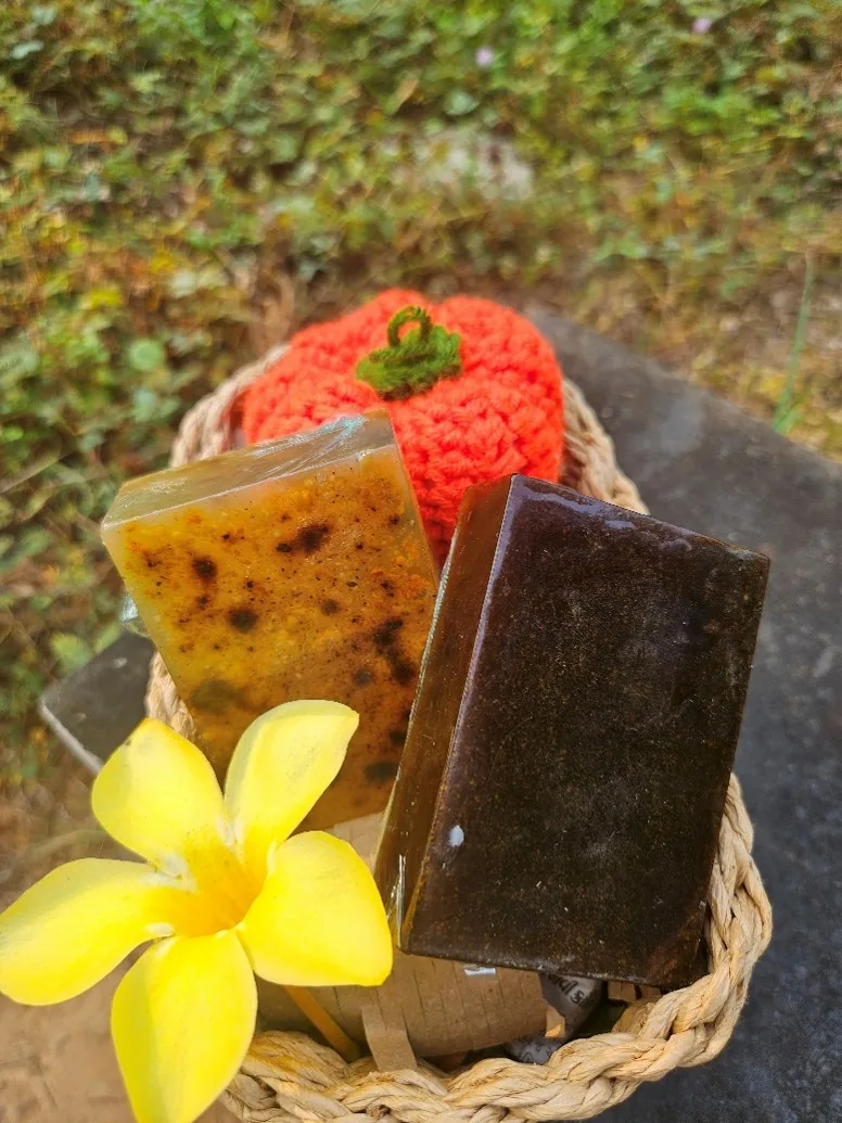 Healing Soil Pomegranate Soap bars in a woven basket with a yellow plumeria flower, green garden backdrop