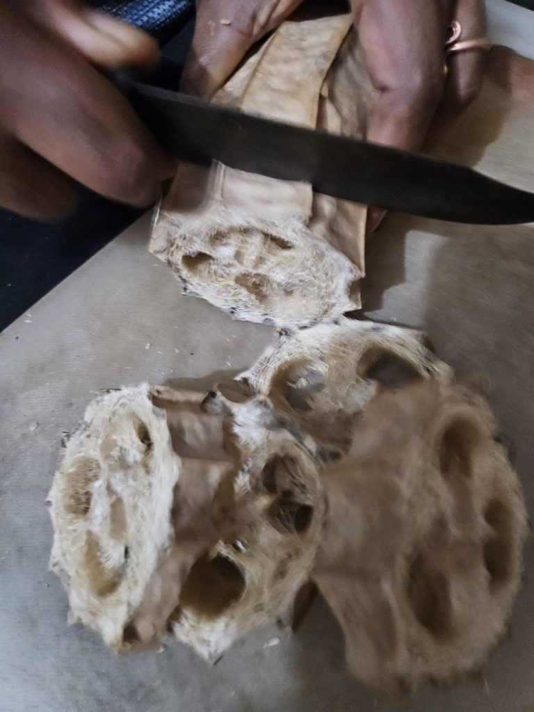 Hands cutting dried ridge gourd loofah into pieces for homemade exfoliating soap scrub - zero waste bathroom DIY