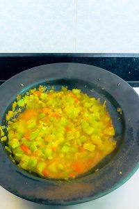 Vegetables cooking in their own natural juices in a steel pan, demonstrating mindful fire element cooking practices for mental health
